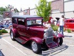 A classic Ford something-or-other with locals and the Harley shop behind.